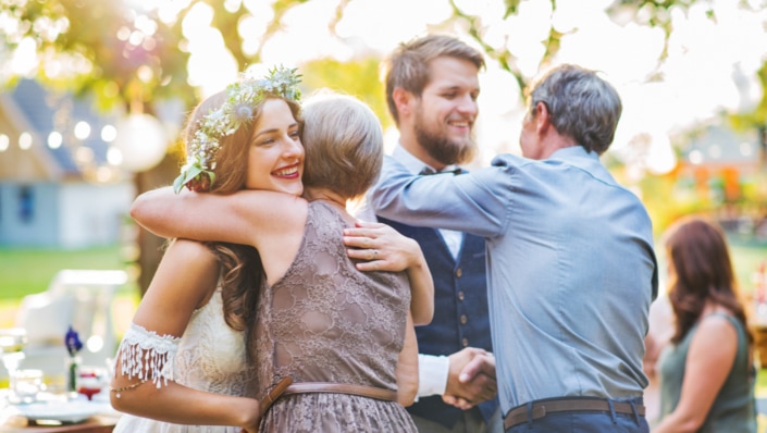 Guests congratulating bride and groom at wedding reception outside in the backyard.