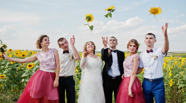 Wedding couple, groomsmen and bridesmaids throwing sunflowers in